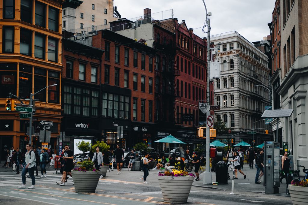 Vibrant urban street scene in New York City with people walking among historic buildings.